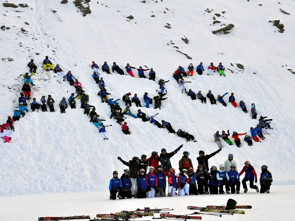 Gruppe jubelt vor dem Schriftzug ARS im Schnee.